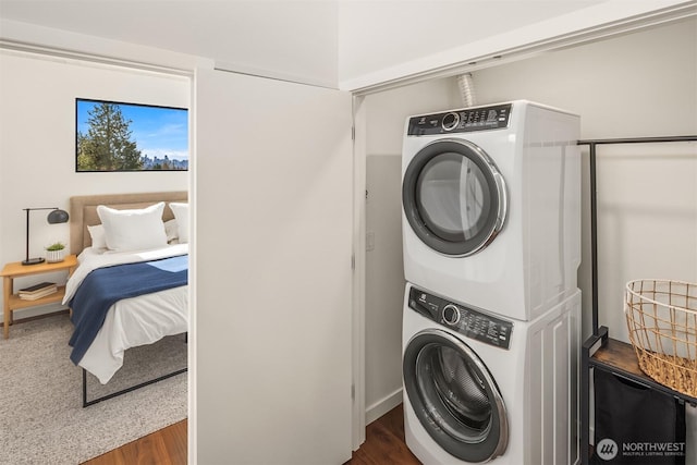 washroom featuring laundry area, stacked washer / dryer, and wood finished floors