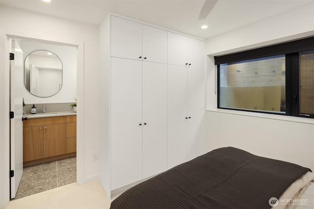 bedroom with a closet, light tile patterned floors, recessed lighting, and ensuite bath