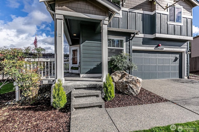 entrance to property featuring a porch, concrete driveway, and a garage