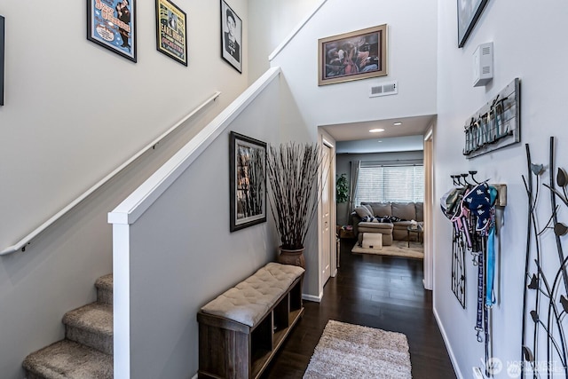 entrance foyer with stairway, baseboards, visible vents, a high ceiling, and dark wood-style flooring