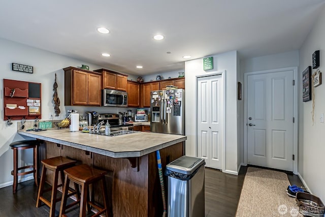 kitchen featuring a peninsula, a breakfast bar area, dark wood-style flooring, and stainless steel appliances