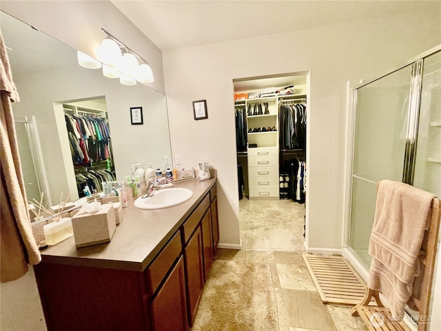 full bath with a spacious closet, a shower stall, vanity, and baseboards