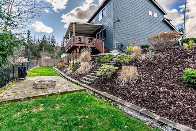 rear view of property featuring a patio, a fenced backyard, a fire pit, a wooden deck, and stairs