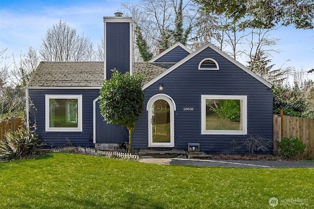 view of front of property with a chimney, a front lawn, and fence