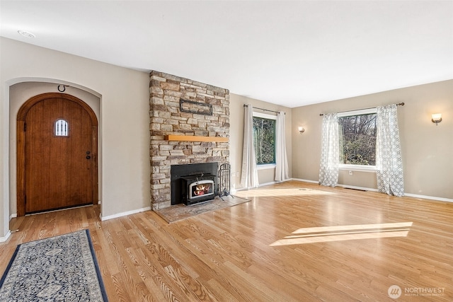 unfurnished living room with baseboards, arched walkways, and wood finished floors