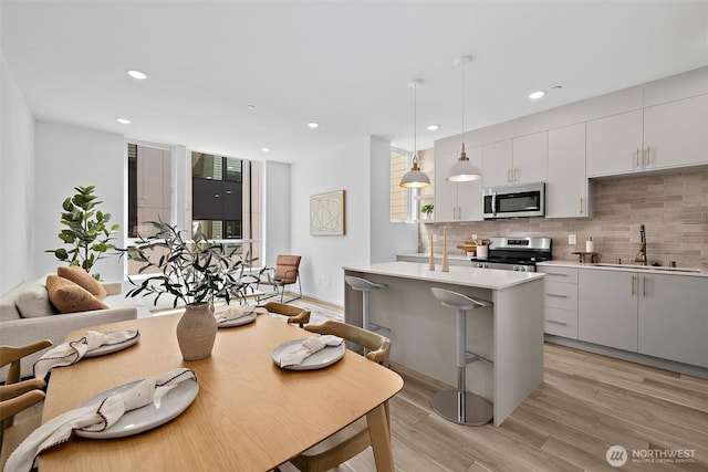 kitchen featuring decorative backsplash, a sink, light wood finished floors, and stainless steel appliances