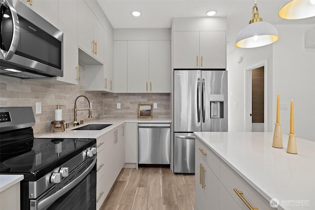 kitchen featuring a sink, light countertops, decorative backsplash, and stainless steel appliances