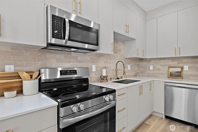 kitchen with a sink, decorative backsplash, light countertops, and stainless steel appliances