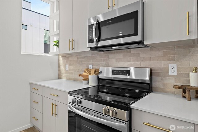 kitchen with stainless steel appliances, white cabinets, decorative backsplash, and light countertops