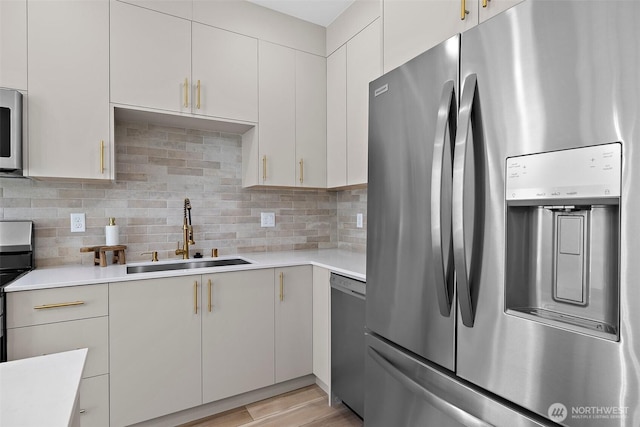 kitchen with tasteful backsplash, dishwashing machine, stainless steel fridge, and a sink