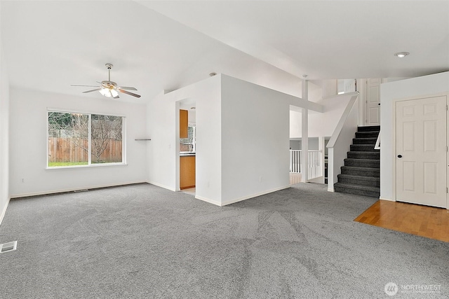 unfurnished living room featuring visible vents, carpet floors, baseboards, and stairs