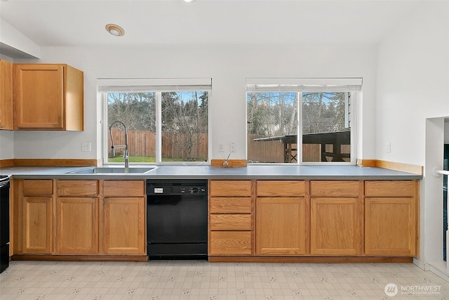 kitchen featuring light floors, black dishwasher, and a sink