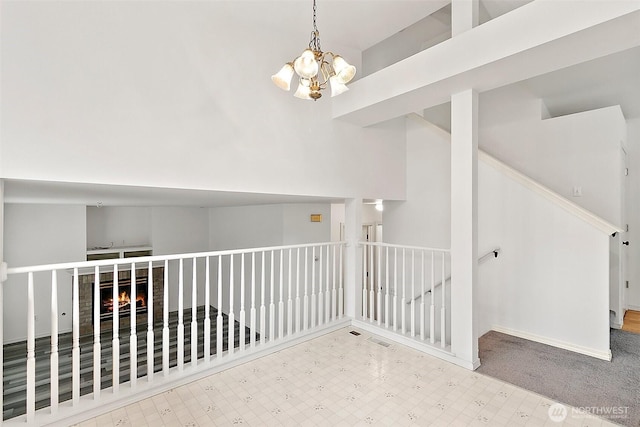 hall with tile patterned floors, baseboards, and a notable chandelier