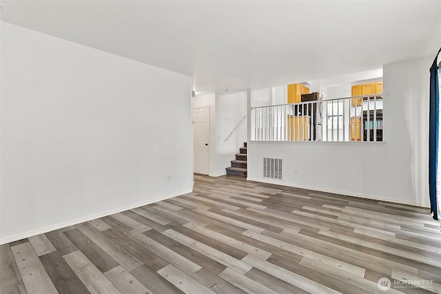 unfurnished room with visible vents, stairway, baseboards, and wood finished floors