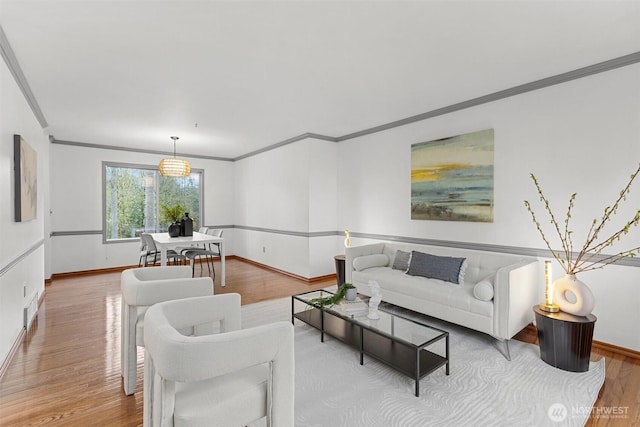 living room with crown molding, wood finished floors, baseboards, and visible vents