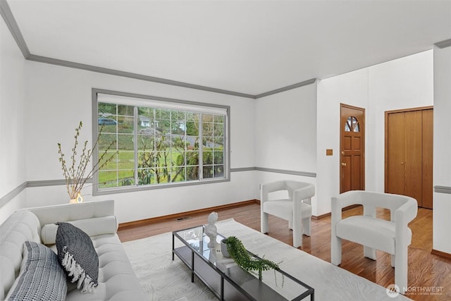 living area featuring visible vents, crown molding, baseboards, and wood finished floors