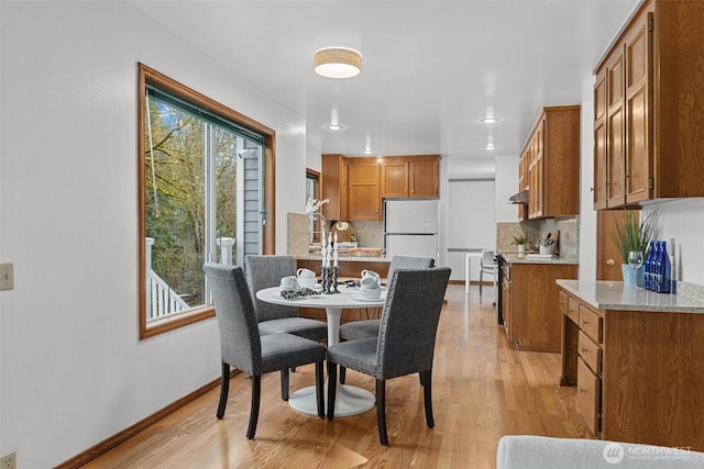 dining space with baseboards and light wood-style floors