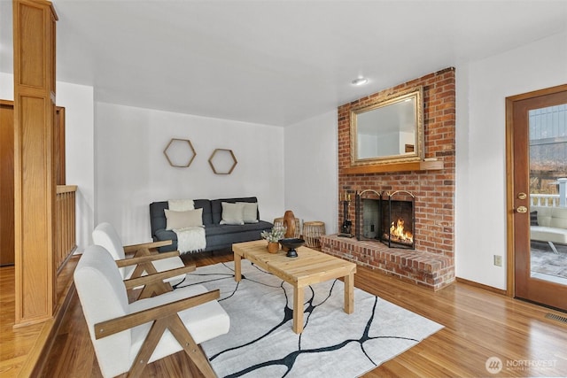 living room with a brick fireplace and light wood-style floors