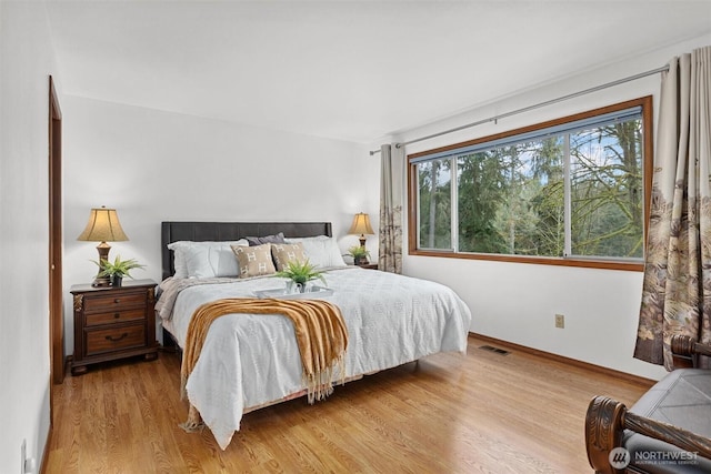 bedroom featuring visible vents, baseboards, and light wood finished floors