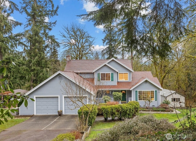 traditional home with a porch, driveway, a chimney, and a garage