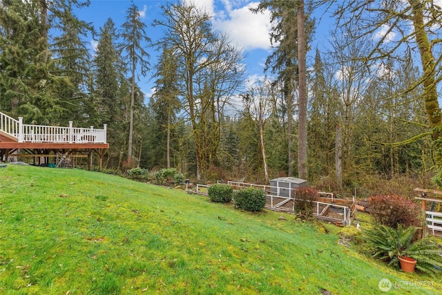 view of yard with a forest view, an outdoor structure, and a deck