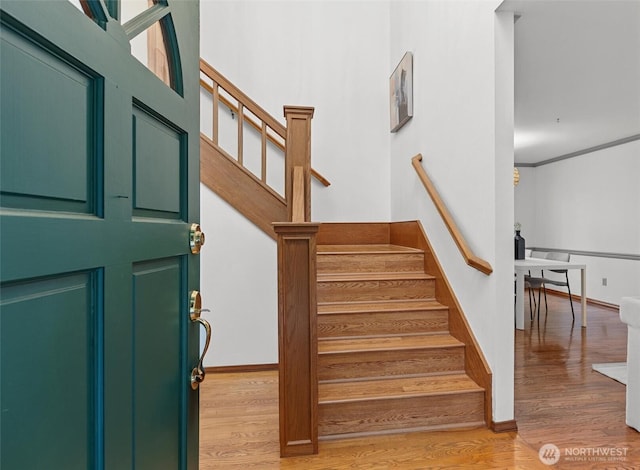 foyer entrance featuring light wood-style flooring, stairs, and baseboards