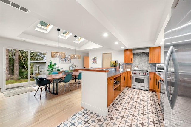 kitchen with a raised ceiling, a peninsula, visible vents, and stainless steel appliances