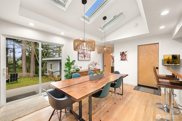 dining space with a raised ceiling, light wood-style flooring, and recessed lighting