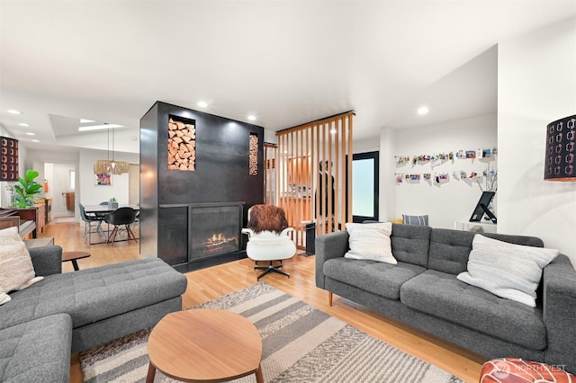 living room with recessed lighting, a fireplace with flush hearth, and wood finished floors