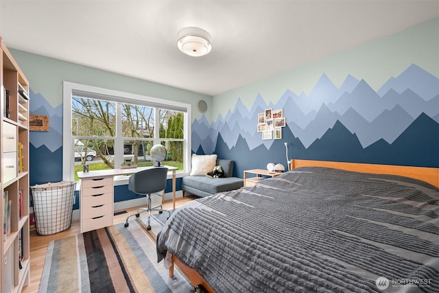 bedroom with baseboards, wood finished floors, an accent wall, and wallpapered walls