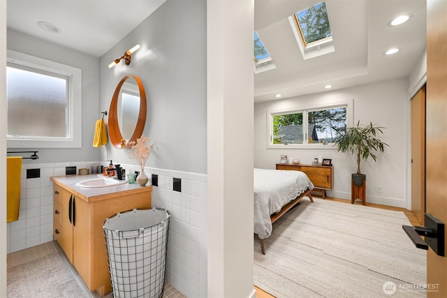 bathroom with recessed lighting, tile walls, a skylight, and vanity