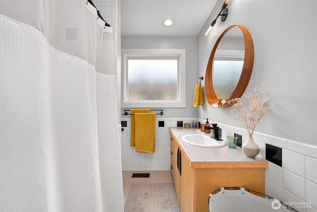 full bath with vanity, a wainscoted wall, visible vents, tile walls, and tile patterned floors