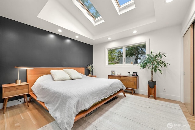 bedroom featuring lofted ceiling, recessed lighting, light wood finished floors, baseboards, and an accent wall