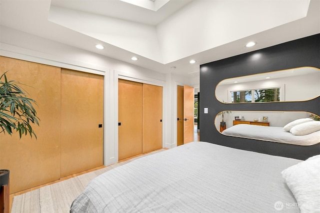 bedroom featuring a skylight, a towering ceiling, recessed lighting, and two closets