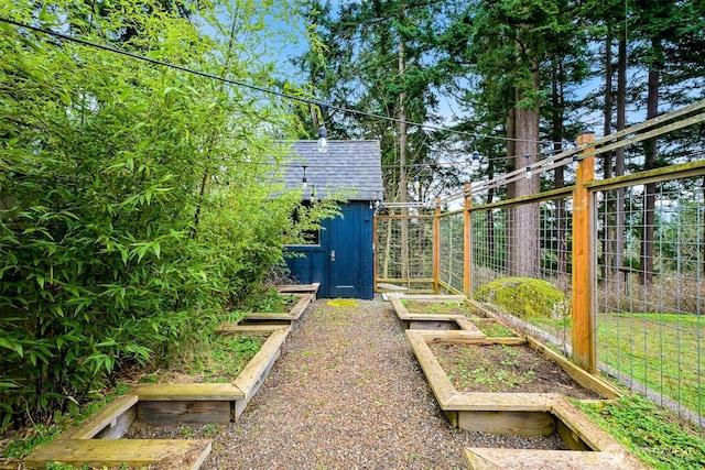 view of yard featuring an outbuilding, a vegetable garden, fence, and a shed