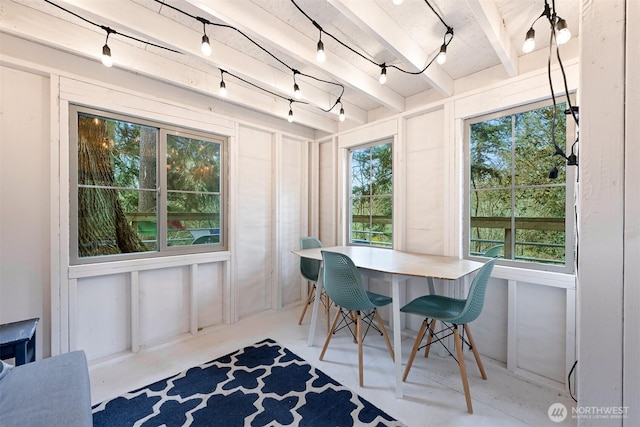 dining space featuring beamed ceiling, track lighting, and concrete floors