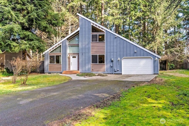 mid-century inspired home featuring board and batten siding, a front yard, a garage, and driveway