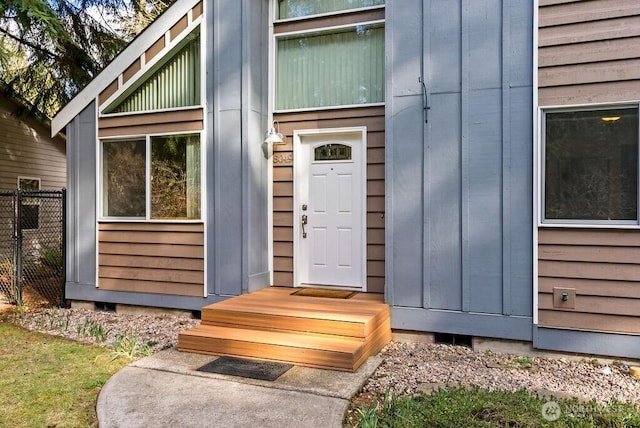 doorway to property with fence and board and batten siding