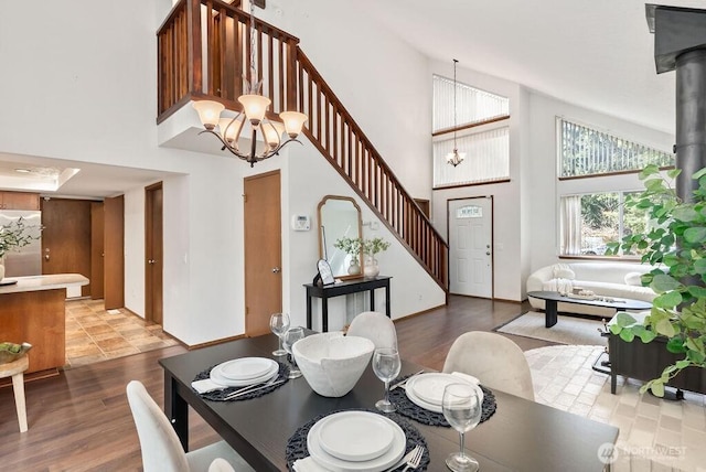 dining room with stairway, wood finished floors, a wood stove, a towering ceiling, and a notable chandelier