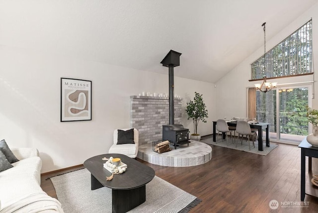 living area featuring wood finished floors, baseboards, high vaulted ceiling, a wood stove, and a chandelier