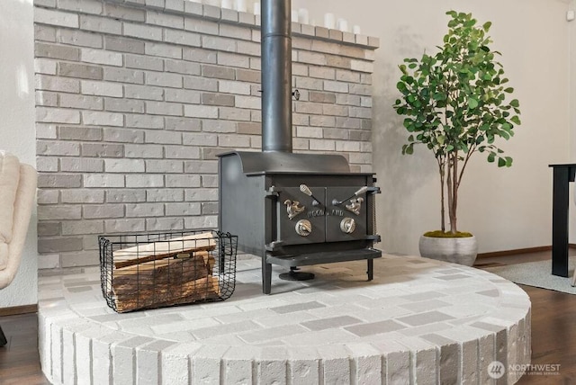 interior details with a wood stove, baseboards, and wood finished floors