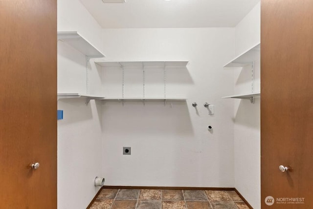 laundry room with electric dryer hookup, washer hookup, stone finish floor, baseboards, and laundry area