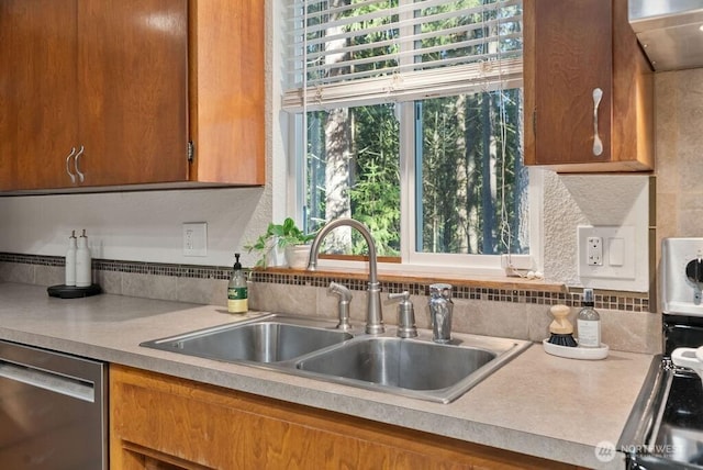 kitchen with stainless steel dishwasher, light countertops, range hood, and a sink