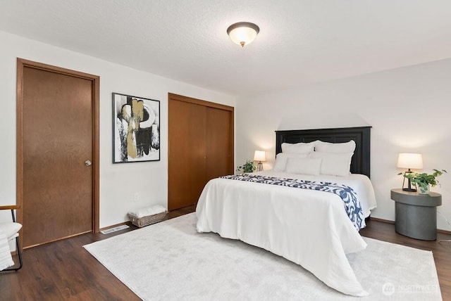 bedroom with a closet, visible vents, a textured ceiling, and wood finished floors