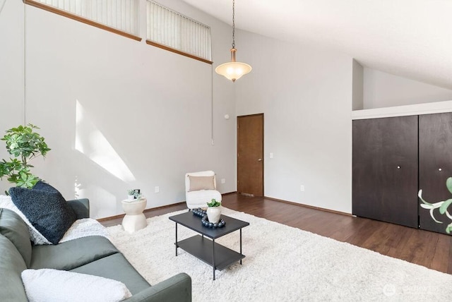 living area with wood finished floors, baseboards, and high vaulted ceiling