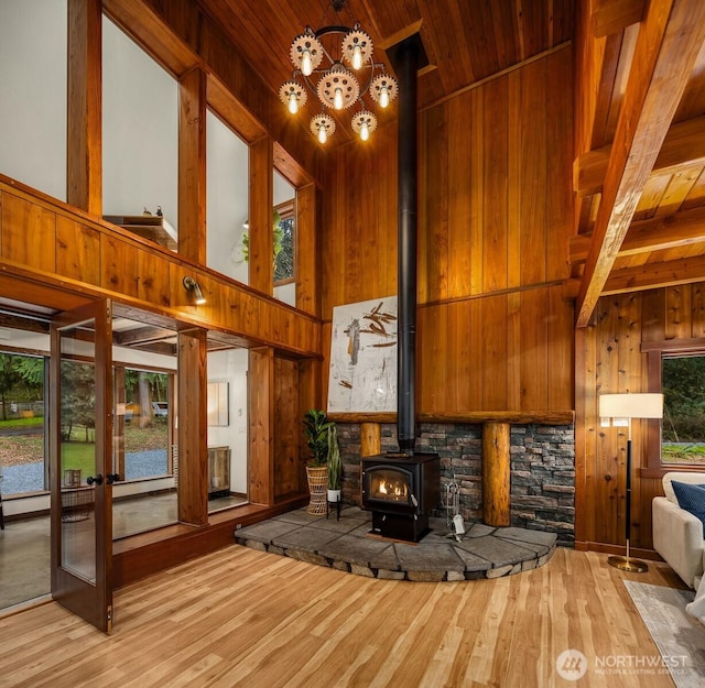 unfurnished living room featuring a towering ceiling, wood walls, and wood ceiling