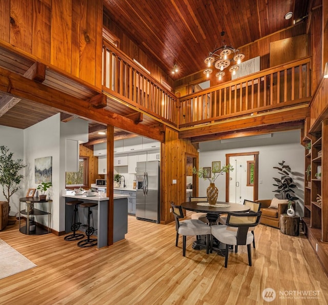 dining area featuring a high ceiling, light wood-style flooring, and wood ceiling