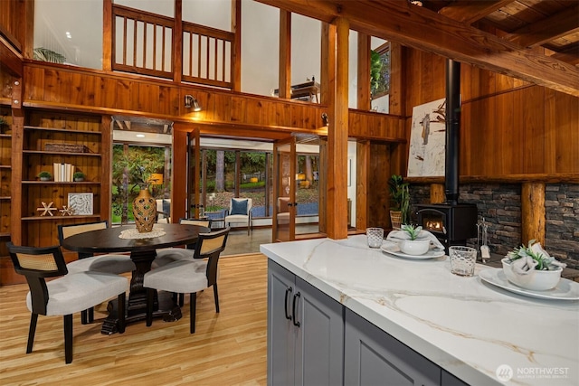 kitchen with a towering ceiling, light stone counters, and a wood stove