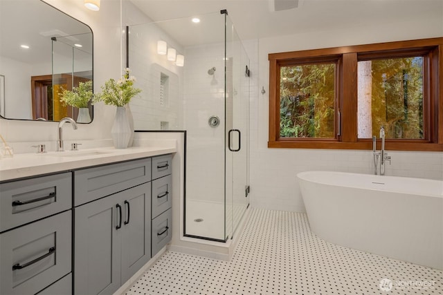 full bathroom featuring vanity, a shower stall, a soaking tub, recessed lighting, and tile walls