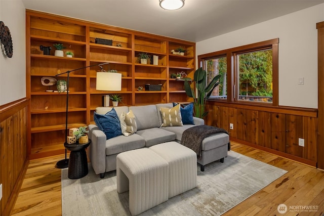 living area featuring light wood-style flooring, wainscoting, and wood walls
